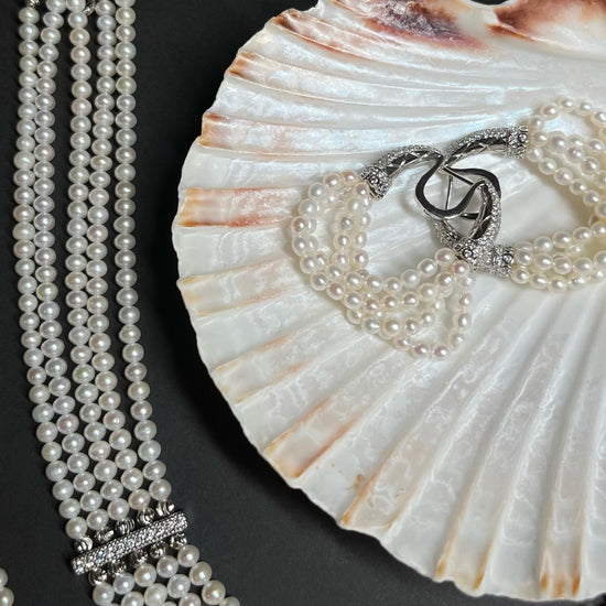 The Interlace Pearl Necklace displayed with shell and pearl earrings