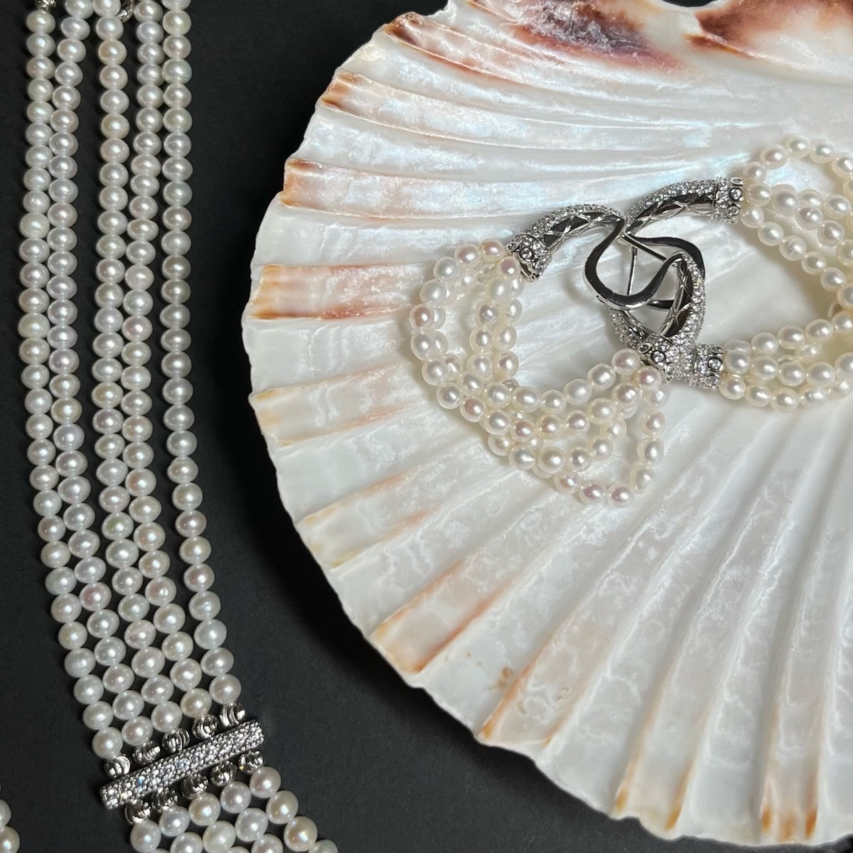 The Interlace Pearl Necklace displayed with shell and pearl earrings