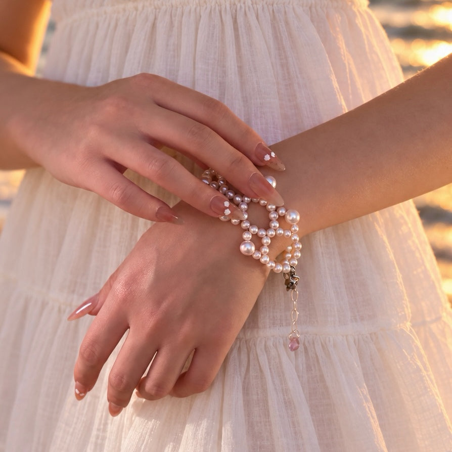 Ballet Rosé pink pearl weave bracelet worn with a white dress, showing the adjustable extender