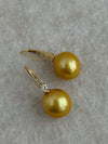 Close-up of natural golden pearl and gold-plated silver hook with cubic zirconia
