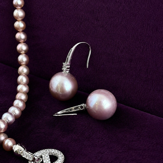 Natural purple pearl sterling silver drop earrings on violet velvet, showing pearl shape and lustre