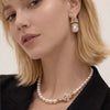 Model wearing NINEMOO Iris gold-tone pearl drop earrings and matching pearl necklace with a black jacket