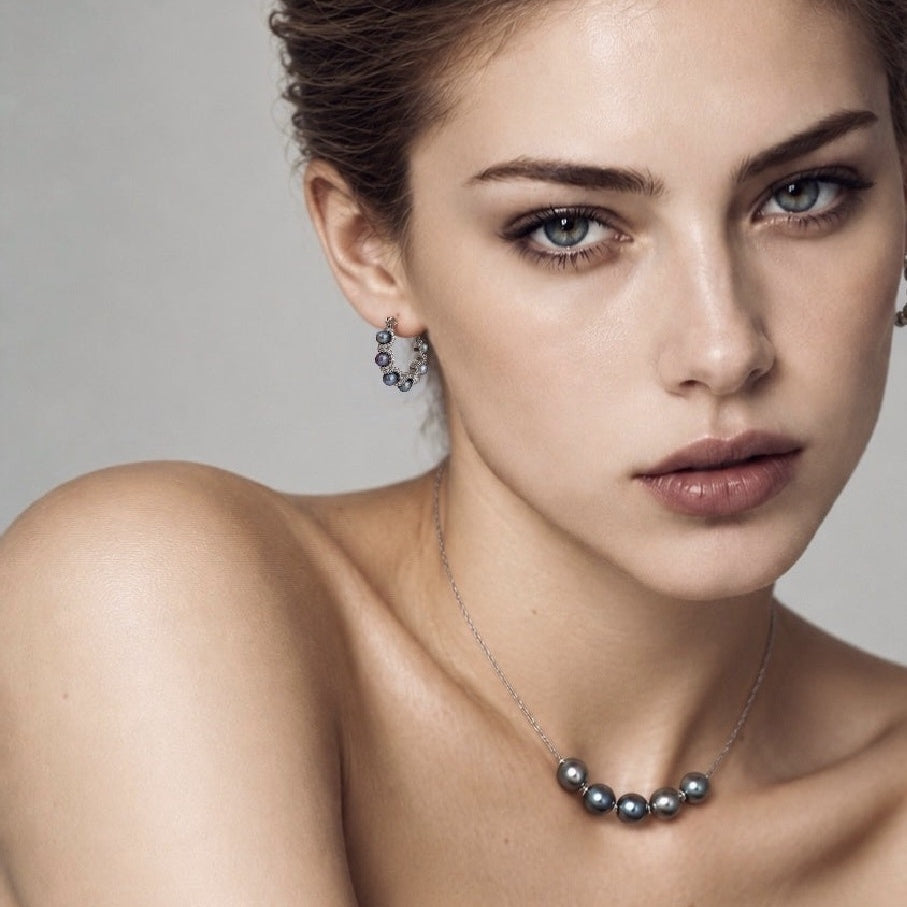 Model wearing Nacre Noire peacock pearl hoops with a complete five-pearl necklace