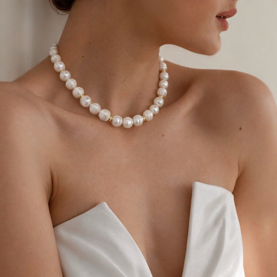 Pearl of Eternity Necklace in white by NINEMOO worn with a strapless white top, showing freshwater pearls and gold spacers.