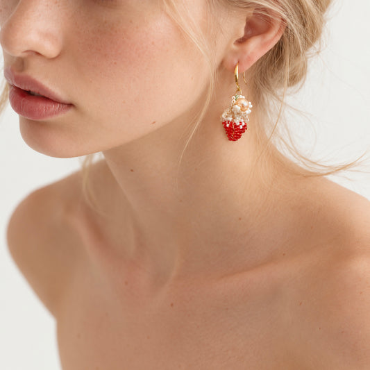 Strawberry Pearl Dangle Earrings by NINEMOO worn on the ear, showing the shorter earring with red beaded strawberry and pink pearl.