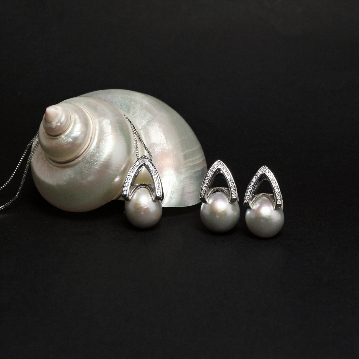 Arché silver grey pearl earrings and necklace on a pale shell